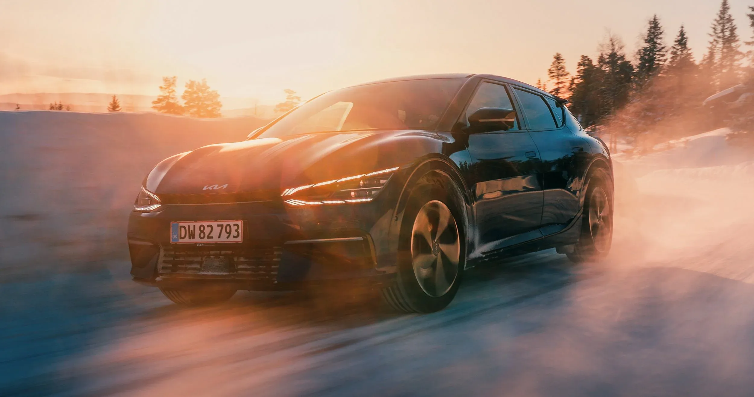 Kia EV6 i fuld fart gennem sne og modlys ved solnedgang